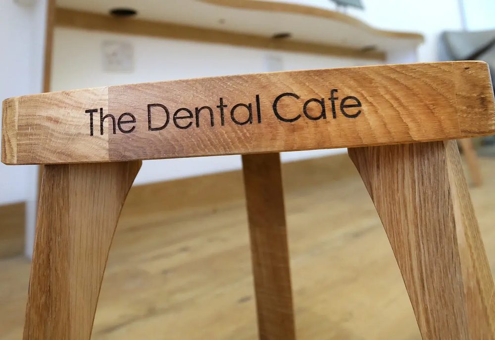 A wooden chair with The Dental Cafe engraved into the seat.