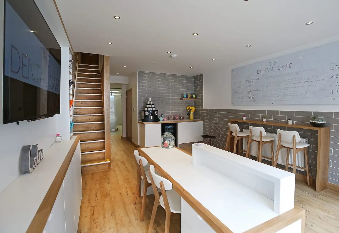 The waiting area at The Dental Cafe: a wooden communal table, bar stools, a coffee machine and a hygiene menu board on the wall.